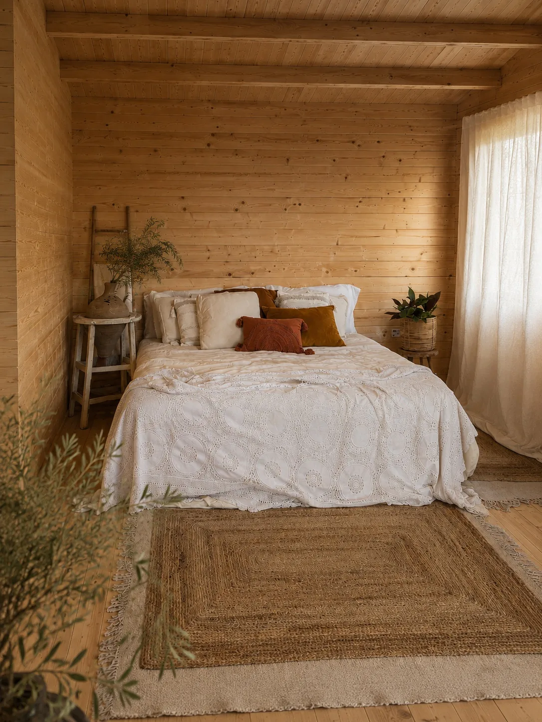 Interior del estudio de fotografía de Isaloclick en Campodón: cabaña de madera con cama, cojines terracota y alfombra de yute